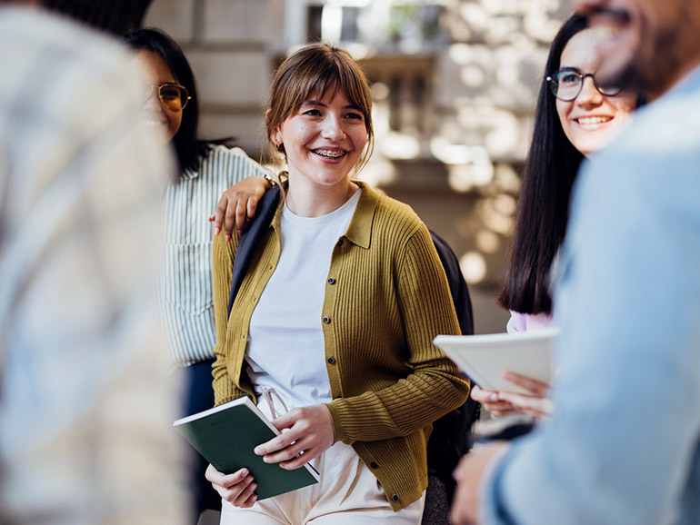 Eine Studentin im Gespräch mit vier anderen Studierenden