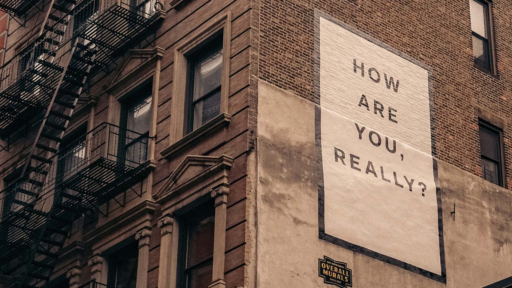 Eine Wand eines Wohngebäudes mit dem Schriftzug "How are you, really?"