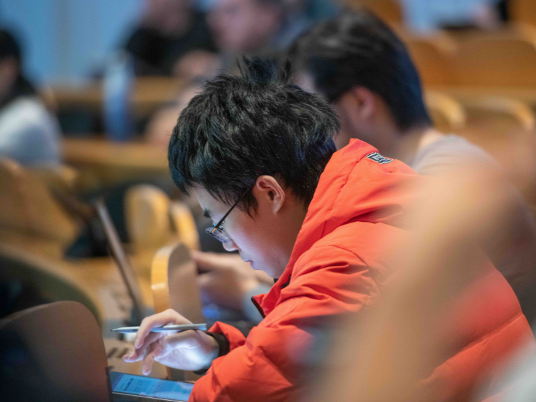 Student, der konzentriert Notizen macht während einer Vorlesung