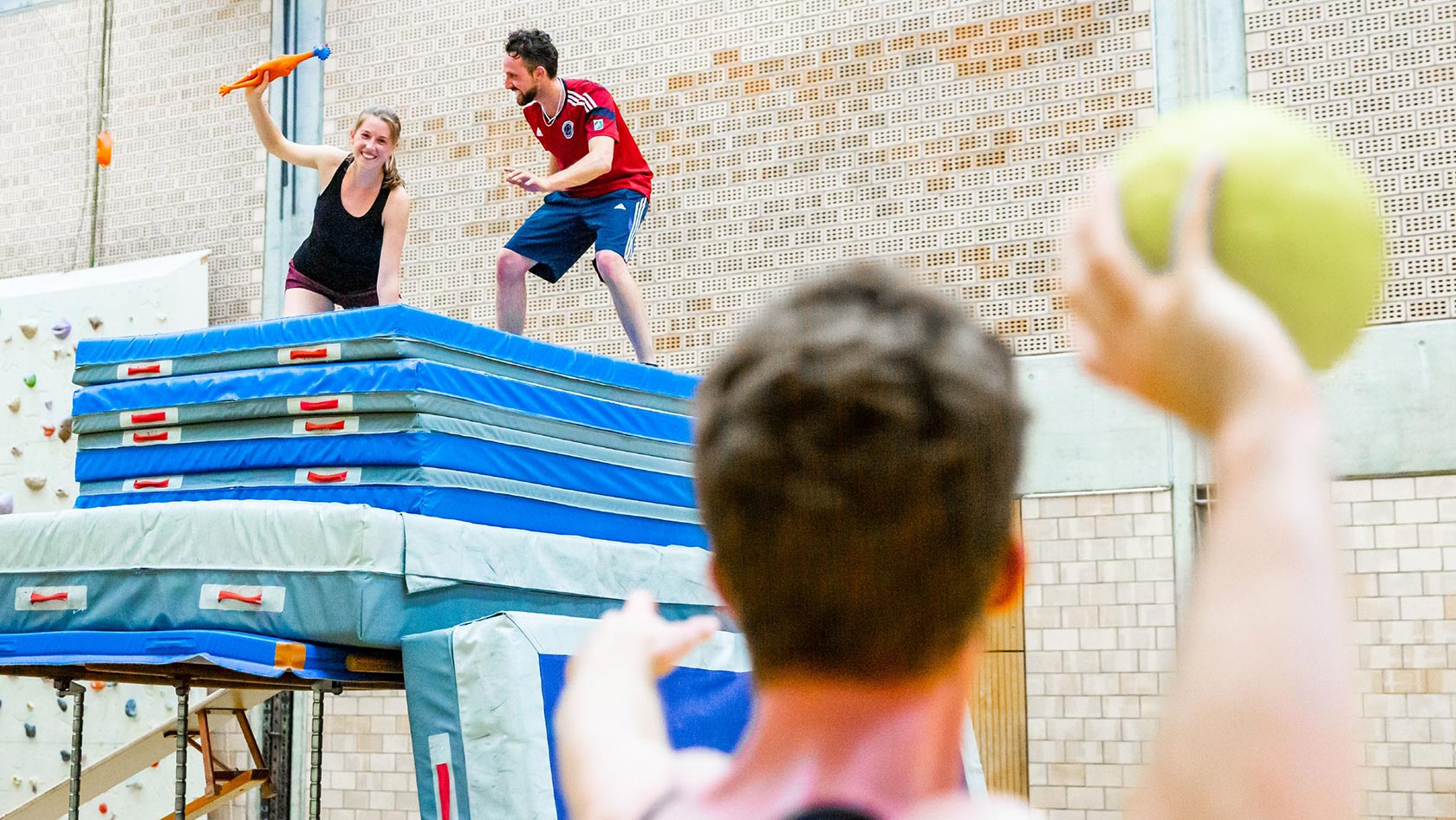 Drei Personen spielen ein Völk in einer Sporthalle